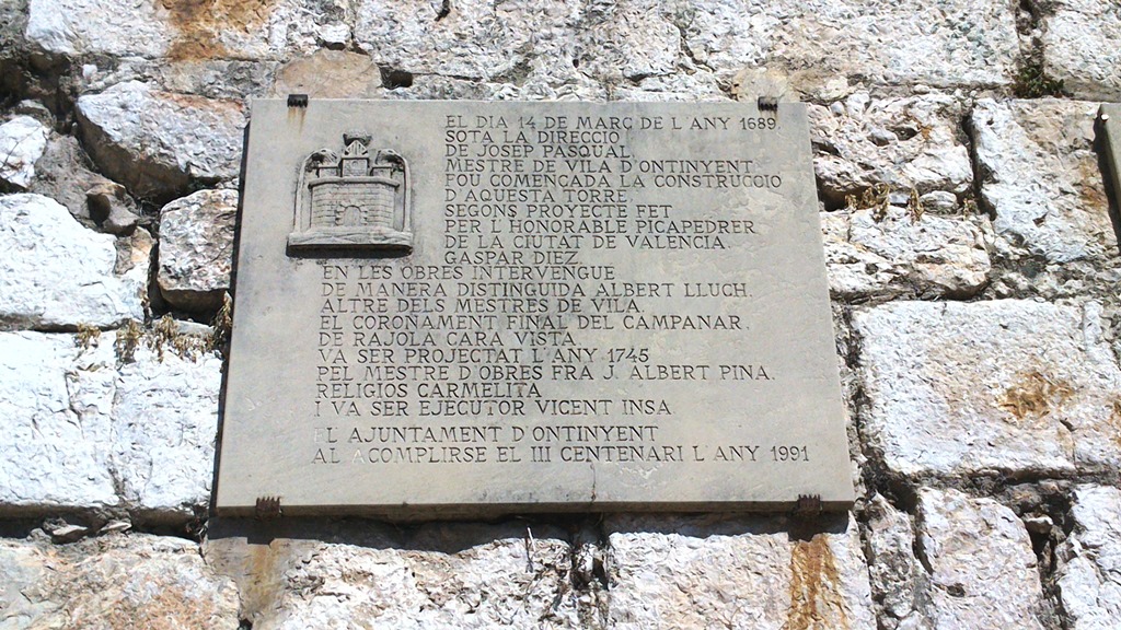 Placa que recuerda el 300 aniversario del inicio de la construcción de la Torre. Se puede ver al pie del Campanario, en la calle Regall.